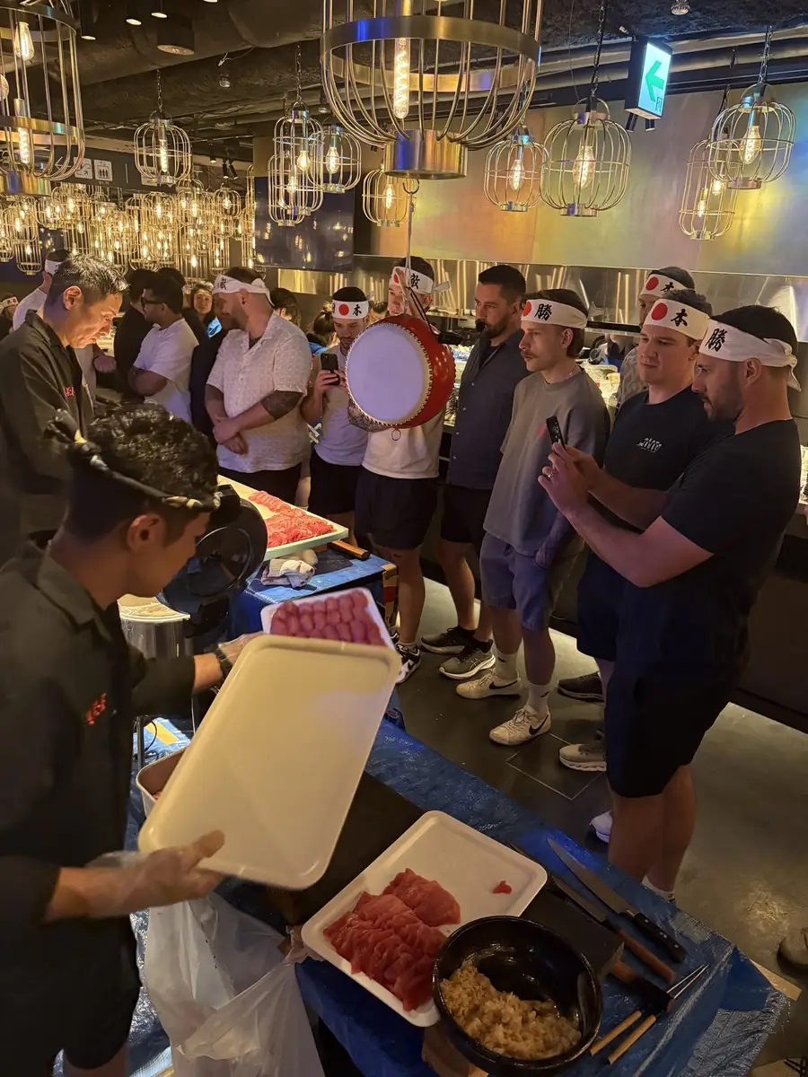 Guests crowded around a private tuna-cutting show under paper lanterns