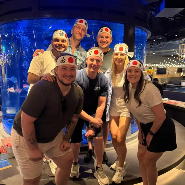 A team in headbands in front of a huge blue fish tank