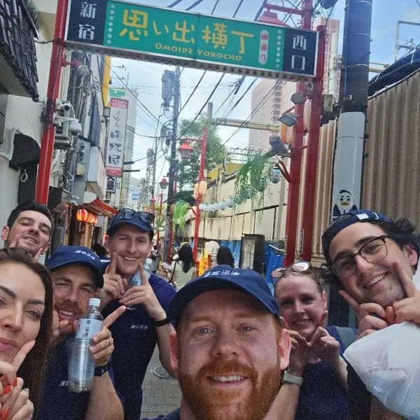 A team selfie in a narrow Shinjuku alley lined with signs
